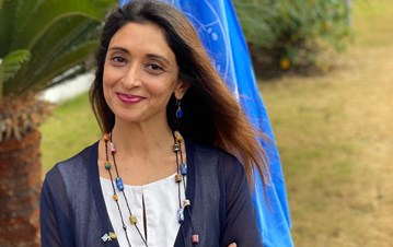 An IIS alumna Zahra Virani wearing a blue-white shirt and posing for a picture 