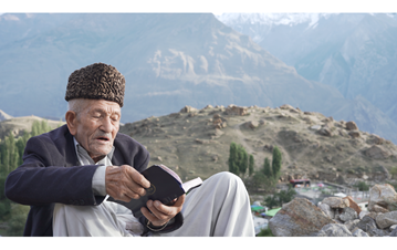 a man in a rural Pakistan reading from his notes for IIS Oral History Project. 