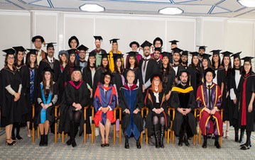 Cohort 12 graduates taking a group photo with the faculties and dignitaries all dressed in graduation gowns on the convocation day