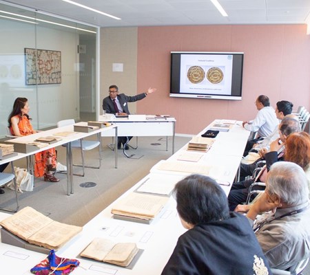 A group of people sitting with manuscripts in a U-shaped classroom and listening to the presentation displayed on the projector by an IIS faculty.